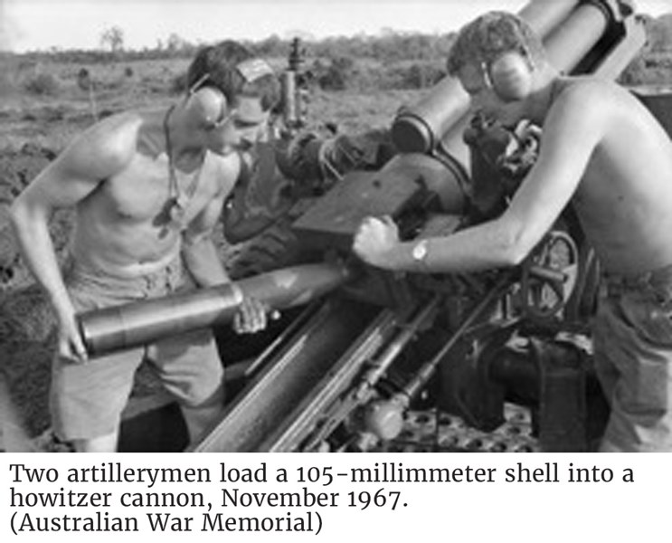 Two artillerymen load a 105-millimmeter shell into a howitzer cannon, November 1967. (Australian War Memorial)